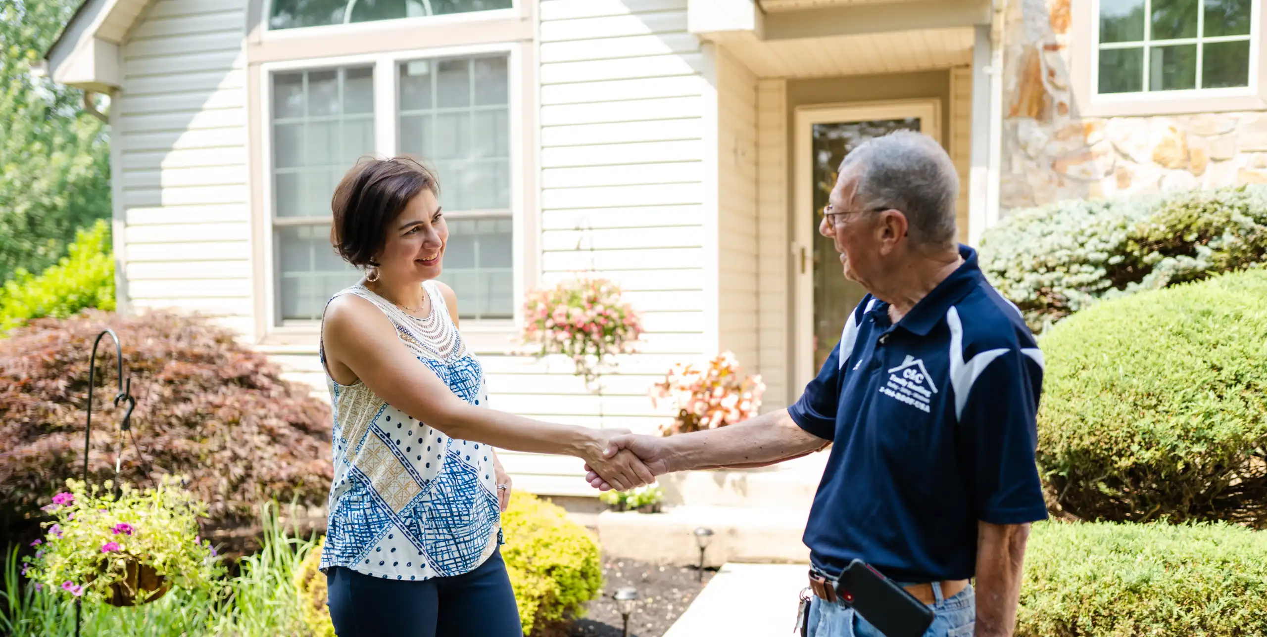 A roofer and a customer talking outside of a house.