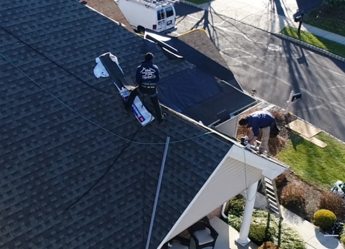 A roofer and a customer talking outside of a house.